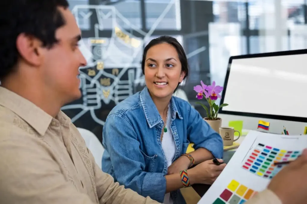 Dos profesionales de diseño colaborando y analizando una paleta de colores en una oficina. Ilustra el trabajo de una agencia de publicidad en Villavicencio enfocada en la creación de branding estratégico para negocios.